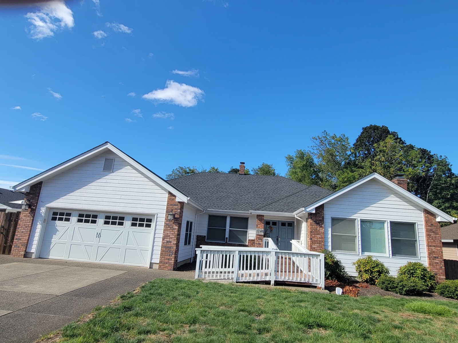 The Lighthouse Home Care Services house: a single-storey home with white siding, brick accents, a two-car garage, and a white wheelchair ramp leading to the front door.